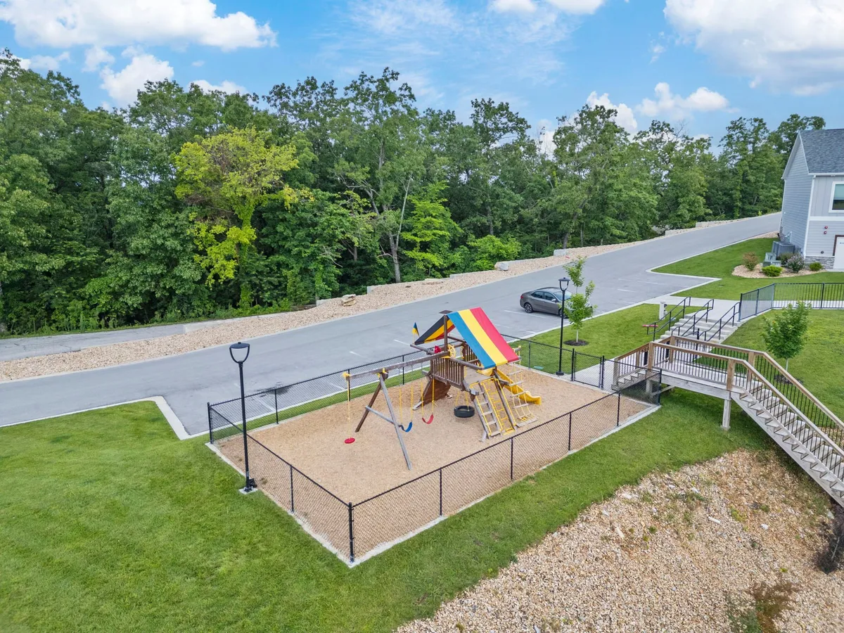 A vibrant playground featuring swings, climbing structures, and a colorful canopy. Children are seen playing and families gather around, reinforcing a sense of community and fun.