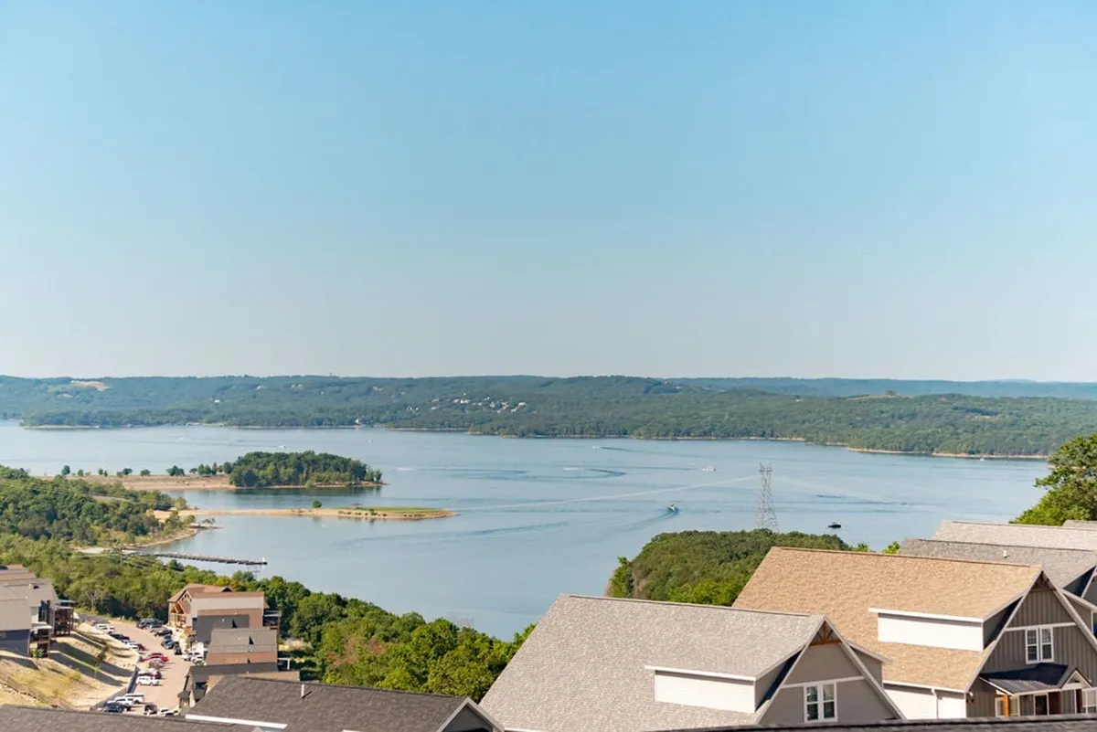 A breathtaking view of the lake with gentle hills in the background, dotted with boats and nearby homes lining the shoreline. The image exudes a peaceful, inviting atmosphere and suggests opportunities for outdoor recreation and scenic relaxation.